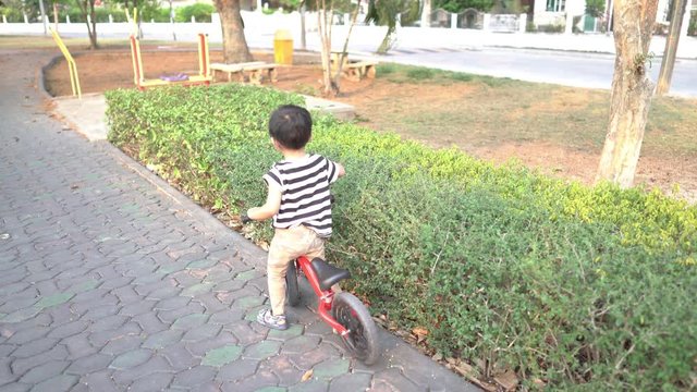 The boy trained to play a balance bike with her older sister tasing care of the garden