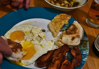 Breakfast with Fried Eggs and Crisp Bacon and English Muffins with Potato Side Dish