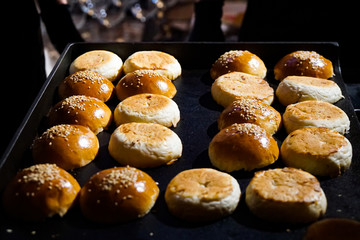 cut burger buns blush on a black baking sheet