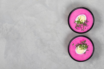 Cold beetroot soup with egg and parsley in a bowl on a light background top view