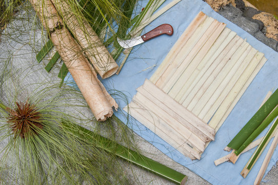 The making of papyrus paper: strips obtained from the stem of papyrus plant with a typical knife and a finished rolled up sheets
