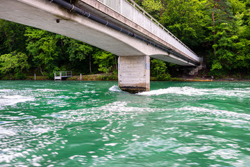 Concrete bridge over the river in a beautiful turquoise color, visible forest along the river.