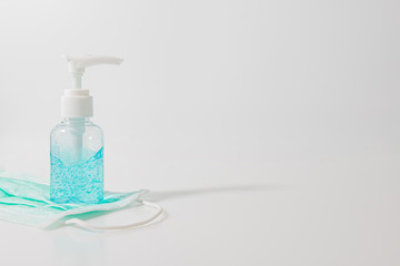 White pump bottle of hand sanitizer gel in  isolated on a white background. and blue medical mask for dust protection and very efficient filtration of airborne particles, covid-19, coronavirus.