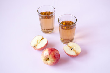 Whole and cut red Apple and two glasses of Apple juice on a pink background