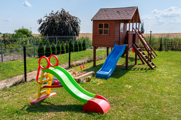Childrens playground by the house garden, visible wooden house, beautiful spring day.