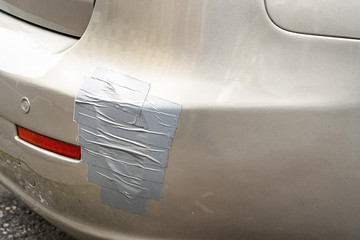 back side of a car automobile, broken car bumper with scotch tape layering stuck covering the scar...