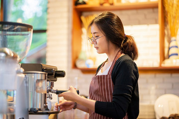 beautiful Asian female barista making cup of coffee for customer, in cafe restaurant, customer service and support, shop business owner working self employed, behind counter with coffee making machine