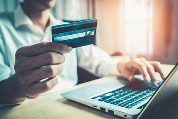 Young man use credit card for shopping payment online on laptop computer application or website....