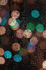 Drops Of Rain On Blue Glass Background. Street Bokeh Lights Out Of Focus. Autumn Abstract Backdrop.Selective focus with noise and grain