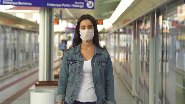 woman at train station in brazil wearing face mask to protect from corona virus. portrait in a busy public place protecting from virus outbreak - health and lifestyle
