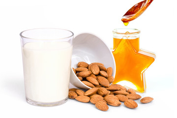 Closeup glass of Almond milk and almond nuts with honey isolated on white background. Healthy drinks concept.