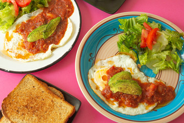 Huevos, recién horneados con una salsa de tomate y una ensalada con aguacate, para una dieta keto o personas fit.