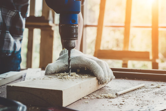Carpenter working on wood craft at workshop to produce construction material or wooden furniture. The young Asian carpenter use professional tools for crafting. DIY maker and carpentry work concept.