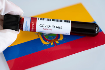 Testing for presence of coronavirus in Ecuador. Tube containing a blood sample that has tested positive for COVID-19. Ecuadorian flag in the background.