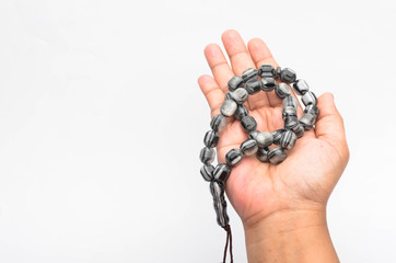 Hand holding muslim beads rosary or tasbih isolated on white background.