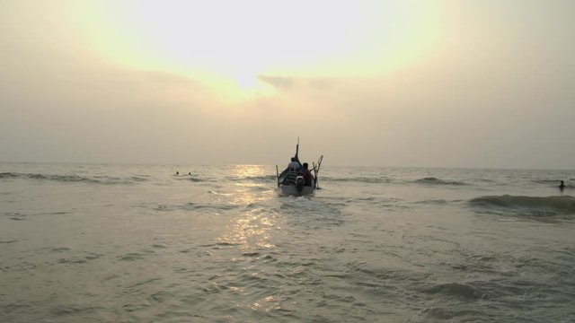 Indian fishermen sail on a boat at sea at sunset. Goa.
