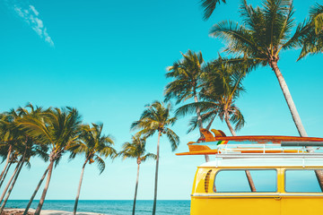 vintage car parked at the tropical beach (seaside) with a surfboard on the roof - Leisure trip in the summer. retro color effect