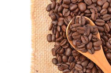 Raw coffee beans with wooden spoon on white background.