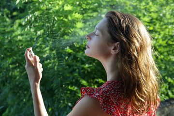 Woman spraying facial mist on her face, summertime skincare concept	