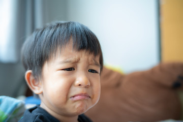 Little asian boy crying bitterly in room of house