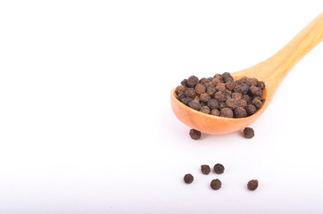 Black peppers on wooden spoon on white background.