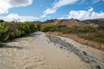 Flooded river with fast flowing dirty silty water after heavy rain