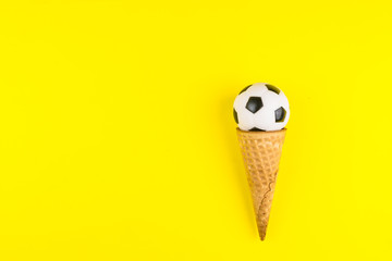 Soccer or football ball in ice cream waffle cone on yellow background in minimal style. Concept sports entertainment. Top view Copy space Template for text or your design.