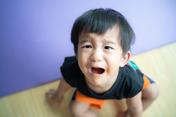Little asian boy crying bitterly in room of house