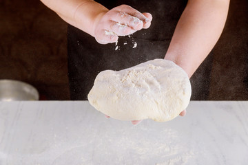 Person kneading pizza dough in hands for making pizza.