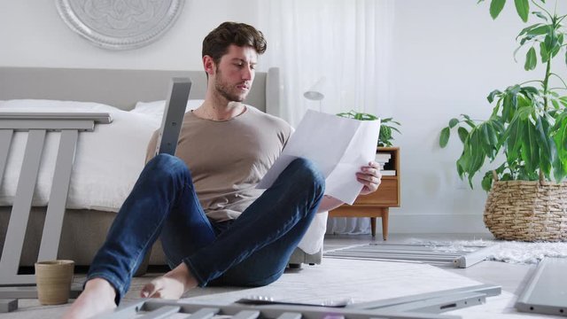 Confused Father To Be Looking At Instructions For Self Assembly Baby Cot