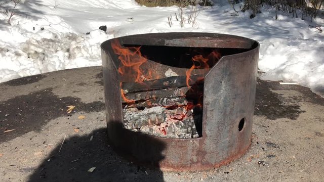 Outside Fire Pit with Fire Burning and Snow in the Background. Winter camping concept. 
