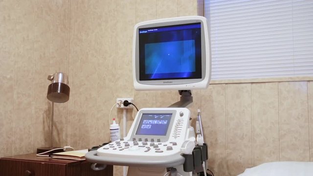 A new, white, modern medical ultrasound machine is located in a bright room. It is connected to a power source, is in working condition. The average plan. Soft light.