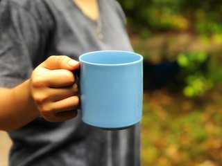 Blue ceramic mug, holding with a female hand