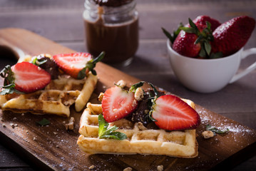 elgian waffles with chocolate sauce and fresh  strawberries on brawn background. Delicious sweet dessert.