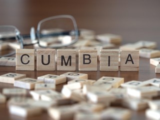 cumbia dance style concept represented by wooden letter tiles on a wooden table with glasses and a book