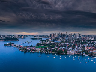 Fototapeta premium Panoramic drone aerial view over Sydney harbour on a cloudy sunset afternoon showing the nice colours of the harbour foreshore