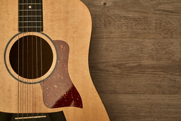 Obraz premium Acoustic guitar body with a red pick guard put down on a brown wooden floor
