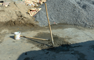 Two hoes of construction workers mixing mortar and sand to repair the house  with crush stone...