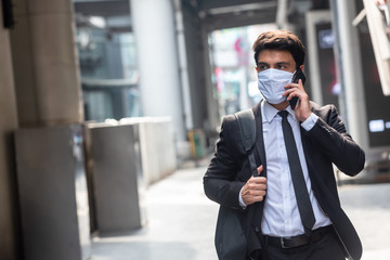 Businessman walking in an empty city during covid-19 outbreak make phone call and wearing white mask