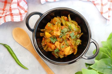 Indian food - Spicy Capsicum and potato stir fried with Indian spices. Aloo and Shimla Mirchi. served in black plate over simple background. 