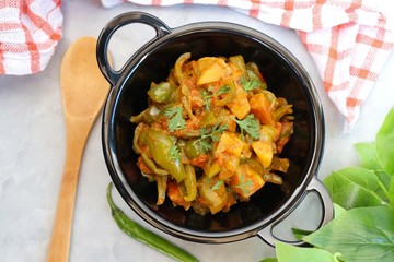 Indian food - Spicy Capsicum and potato stir fried with Indian spices. Aloo and Shimla Mirchi. served in black plate over simple background. 