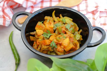 Indian food - Spicy Capsicum and potato stir fried with Indian spices. Aloo and Shimla Mirchi. served in black plate over simple background. 