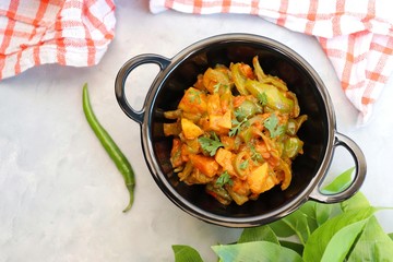 Indian food - Spicy Capsicum and potato stir fried with Indian spices. Aloo and Shimla Mirchi. served in black plate over simple background. 