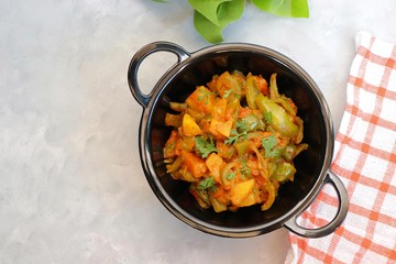 Indian food - Spicy Capsicum and potato stir fried with Indian spices. Aloo and Shimla Mirchi. served in black plate over simple background. 