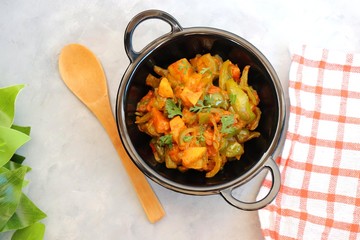 Indian food - Spicy Capsicum and potato stir fried with Indian spices. Aloo and Shimla Mirchi. served in black plate over simple background. 