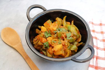 Indian food - Spicy Capsicum and potato stir fried with Indian spices. Aloo and Shimla Mirchi. served in black plate over simple background. 