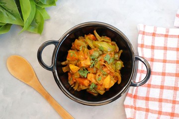Indian food - Spicy Capsicum and potato stir fried with Indian spices. Aloo and Shimla Mirchi. served in black plate over simple background. 
