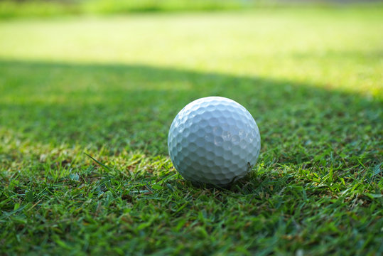 Golf ball on green grass sunset background