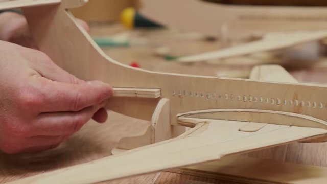 handmade plywood soviet airplane model and man hands inserting miniature details into slot close view slow motion