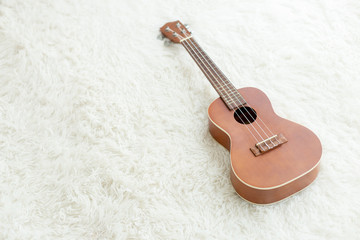 Fototapeta na wymiar ukulele wooden color on white carpet background.